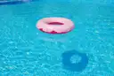 Pink swim ring floating on clear blue pool water