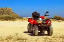 Red ATV with a helmet on the seat, parked on a sandy track