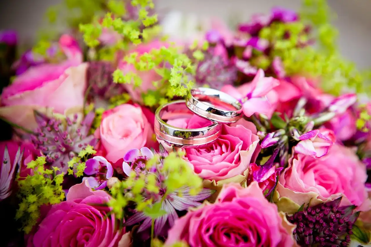 Two wedding rings on a bouquet of pink roses