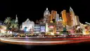 Car light trails streak along the Las Vegas Strip at night past a lit New York-style resort facade