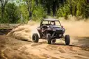 Side-by-side UTV sliding through a dusty dirt bend