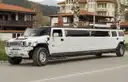 White stretch SUV limousine parked on a street, seen from the front side
