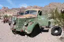 A rusted old pickup truck parked among desert rocks and scrub