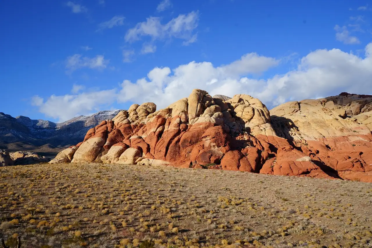Red and cream sandstone hills under a blue sky with white clouds