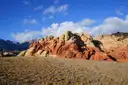 Red and cream sandstone hills under a blue sky with white clouds