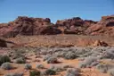 Red rock ridges behind a desert plain dotted with gray-green shrubs