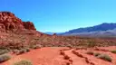 Red sandstone and red desert ground with blue mountains on the horizon