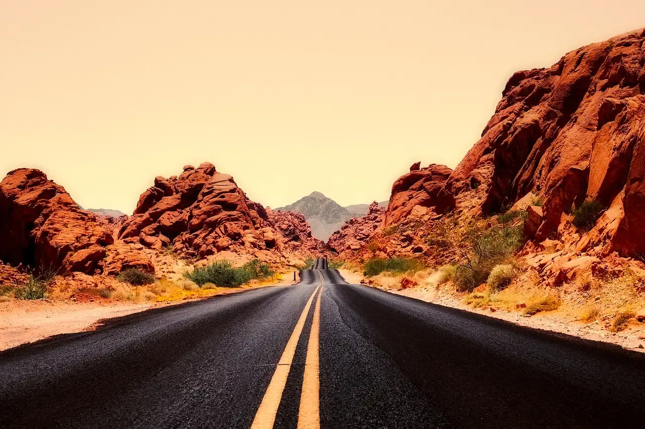 A straight road running between red rock walls under a glowing evening sky