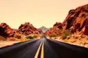 A straight road running between red rock walls under a glowing evening sky