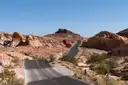A road winding between red and cream sandstone rocks in Valley of Fire under a clear sky