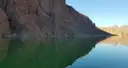 A dark canyon wall reflected in the still green water of the Colorado River at Willow Beach